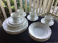 Full set displayed showing all plates, bowls, cups and saucers with white bone china, scalloped edges and glossy finish.