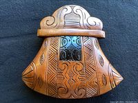 Close view of the top and middle section of the wooden Eskimo Ulu showing fine tribal patterns and polished center panel.