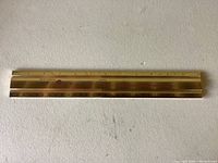 Photo of the full gold tone metal ruler showing measurement scales.