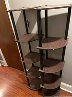 Side angle showing two lightweight plastic corner shelves each with five woodgrain textured quarter-circle shelves and black cylindrical supports.