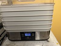 Front view of the base unit featuring stainless steel finish, digital display with timer and temperature, and 6 stacked trays.