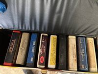 View inside the case showing 8 vintage 8-track tapes with labels from various music collections.