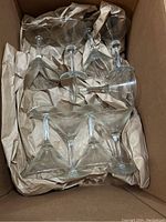 Box containing nine clear martini glasses cushioned with packing paper.