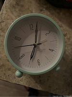 Front view of the mint green analog alarm clock showing the clock face, hour, minute, and second hands.