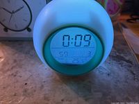 Digital display of alarm clock showing time 0:09, date May 9, Saturday, temperature 25.5C.