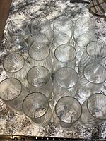 Top view of all 18 glasses arranged closely on a countertop showing both short and tall glasses with ribbed swirled pattern.