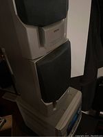 Side view of stacked beige speakers with black mesh fronts on top of stereo main unit.