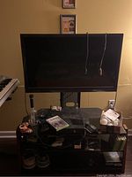 Sony TV and stand with items on the shelves which are not included in the lot. TV is attached to stand, showing overall condition and setup.
