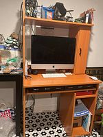 Work desk shown with computer and keyboard on the main surface, various items on the shelf and cabinet above, and open keyboard drawer with compartments visible.
