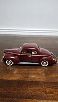 Side view of maroon 1940 Ford Coupe 1/18 scale diecast model on wood floor.