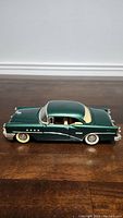 Side view of the 1955 Buick Century 1/18 scale model showing dark green paint, beige parts, and white wall tires.