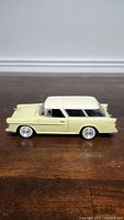 Side view of the yellow and white 1/24 scale model Chevrolet Bel Air Nomad showing detailed side panels and wheels.