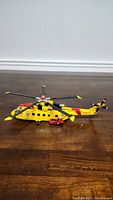 Side view of a detailed yellow and red Canadian Forces rescue helicopter model with small red vehicle next to it