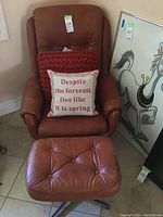 Full view of orange chair with matching footstool and two pillows, showing the condition and style.