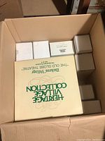 Open cardboard box showing large Heritage Village Collection box and smaller white boxes