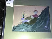 Close-up of framed cel showing two mice on a leaf with water background and mat board.
