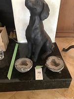 Full lot showing the matte black dog statue sitting with two geode halves in front of it on a black stone surface.