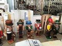 Six nutcracker figurines in a row on floor against stacked boxes