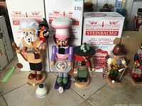 Front row display of Geppetto, chef, Boy Scout and hiker figures with Steinbach boxes behind