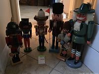 Photo showing seven different nutcracker soldiers lined up on a tile floor, displaying size variations and styles