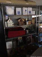 Photo showing metal wire storage rack with items on shelves for scale and context. Shelves contain various household items, but only the rack is for sale.