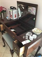 Vanity top with open compartments and associated small glass items (not included) alongside the bench with upholstered seat.