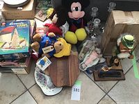 Wide view of lot showing stuffed animals, sailing models, plates, and boxed items on tiled floor