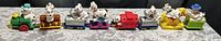 Wide shot of six colorful plastic train cars each featuring dalmatian dog figures in different poses and colors.