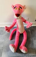Large vintage DAKIN Pink Panther plush in sitting position on grey carpet, showing full front view and details