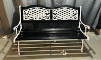 Front view of black and white decorative indoor/outdoor bench showing wooden slat seat and ornate metal backrest.