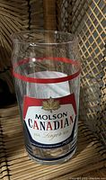 Single clear glass with Molson Canadian Lager logo, featuring a red maple leaf and red stripe around the top.