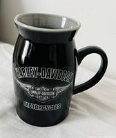 Front view of black Harley-Davidson mug with logo and motorcycle text on front.