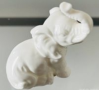 Front-side view of white bone china elephant figurine showing trunk raised and detailed texture.