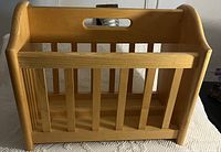 Wooden magazine rack with vertical slats and a handle cut-out on top shown from the front