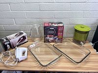 Wide view of all items on table including hand mixer, iron with box, glass baking dishes, plastic pitcher and salad spinner.