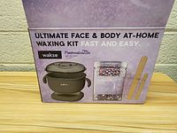 Photo of original packaging box showing brand Wakse, product name Ultimate Face & Body At-Home Waxing Kit, marshmallow & oat scent, and two wooden applicator sticks shown on box graphics.