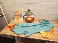 Photo showing the Fortnite Fishstick costume jumpsuit and mask laid out on a table with the product packaging in background.