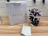 Lenox Jubilee Spirit figurine with original box and certificate on wood surface against brick background.