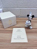 Photo of Mickey Mouse birthday figurine with original box and warranty booklet on table