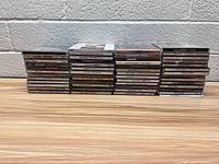 Photo showing three stacks of music CDs on a floor against a white brick wall