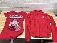 Two pieces of Ohio State Buckeyes apparel: one graphic T-shirt and one zip-up jacket.