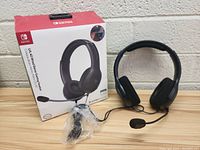 Front view of LALAWO Nintendo Switch Gaming Headphones with box and attached microphone in plastic bag.