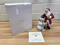 Lot contents showing the Lenox box, Santa and snowman figurine, and informational booklet titled 'The 1999 Lenox Santa'.