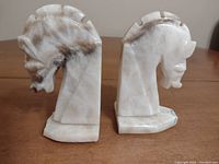 Photo of two alabaster or marble horse head bookends showing their side profiles with natural color marbling and detailing of the mane.