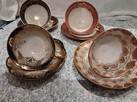 Four bone china teacups on matching saucers showing intricate gold and colored floral and geometric designs from Bavaria, Germany