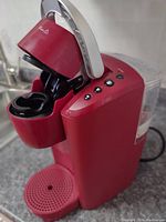 Red Keurig 1st generation coffee machine with open pod holder and control buttons visible, showing machine condition and details.