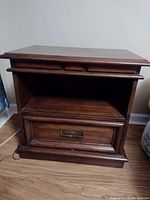Front view of the solid wood end table showing overall structure, top molding, open shelf and drawer with metal handle.