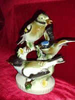 Front and side view of porcelain bird figurine showing three birds in naturalistic pose with detailed painting and flowers on base