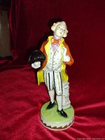 Front view of Royal Doulton porcelain figurine of a gentleman holding a black tricorn hat, with colorful detailed attire.