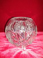 Photo showing a round clear crystal bowl with detailed cut patterns, three small feet, and no visible chips or damage.